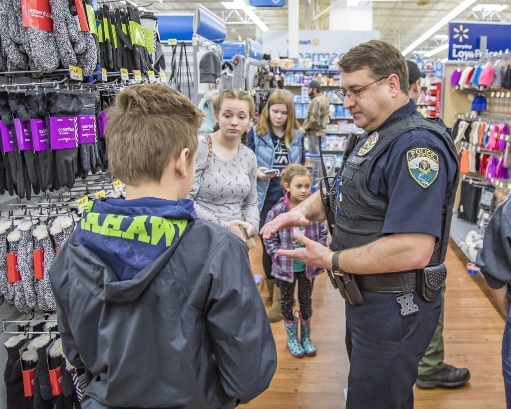 Brent Murray, of the Woodland Police Department, listens intently to his youngster Saturday at the Shop With a Cop event at the Woodland Walmart. Photo by Mike Schultz