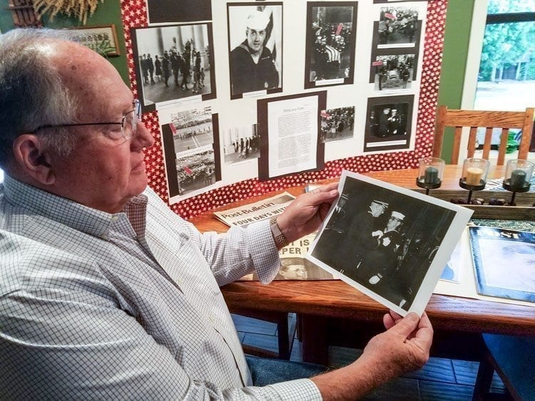 “Bud” Barnum looks at a photograph of him receiving an Army Commendation Medal after his service with the honor guard detail that buried President John F. Kennedy. Barnum was in the U.S. Coast Guard. Photo by Paul Valencia