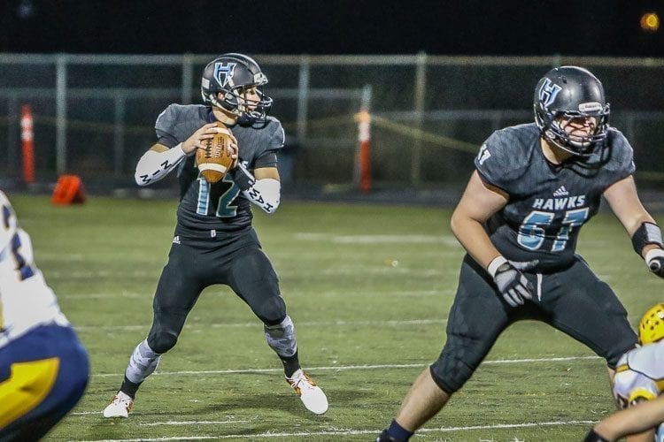 Hockinson quarterback Canon Racanelli (12) is shown here looking for an open receiver in a playoff win over Aberdeen. Providing protection is Hawks lineman Garrett Kondel (67). Racanelli will need time to throw in Saturday’s Class 2A state championship game against Tumwater at the Tacoma Dome. Photo by Mike Schultz