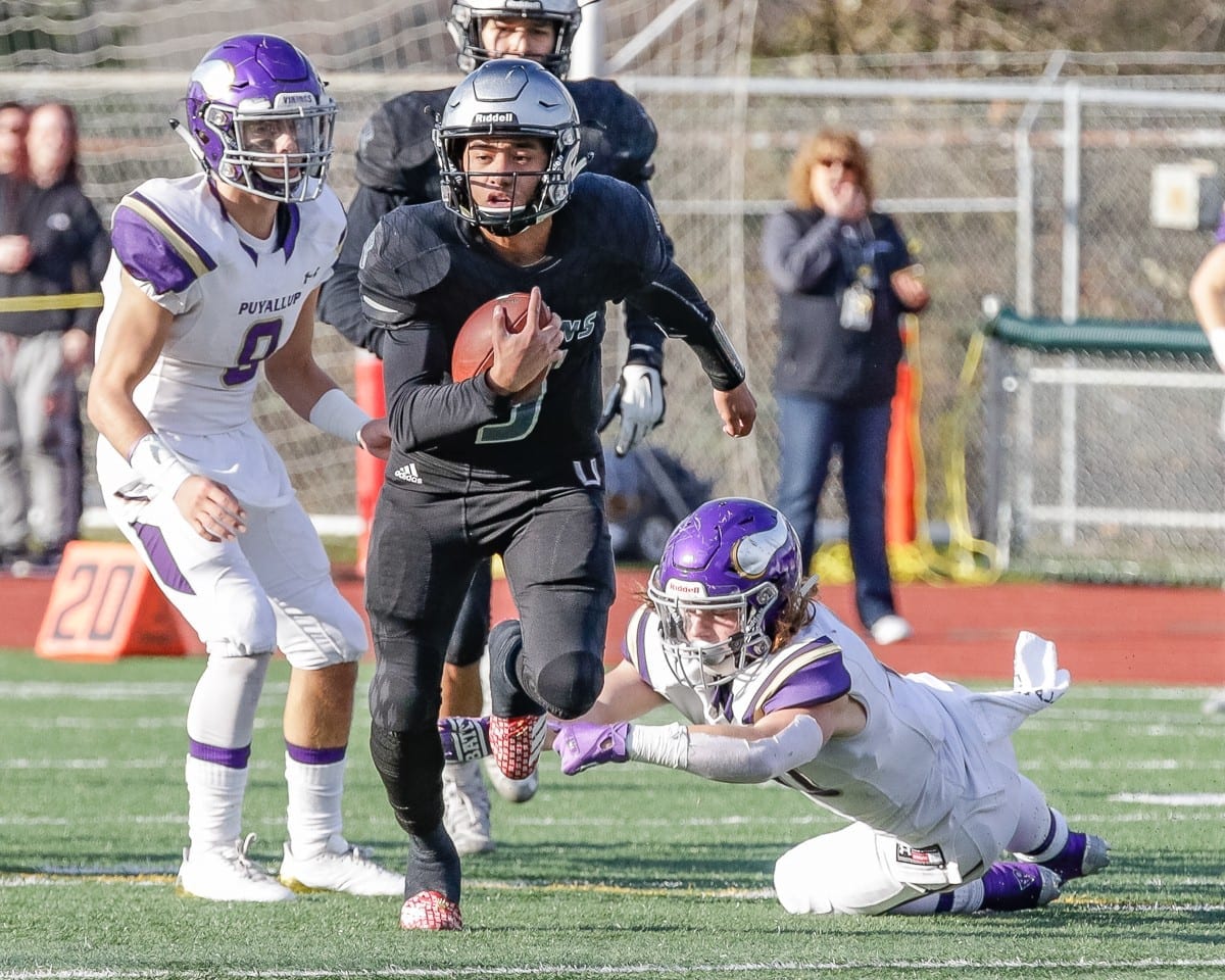 Union quarterback Lincoln Victor (5) breaks away from a pair of Puyallup defenders Saturday. Victor scored the game-winning touchdown with 2:52 left to play to lead the Titans to a 35-28 win in the Class 4A state semifinals at McKenzie Stadium. Photo by Mike Schultz