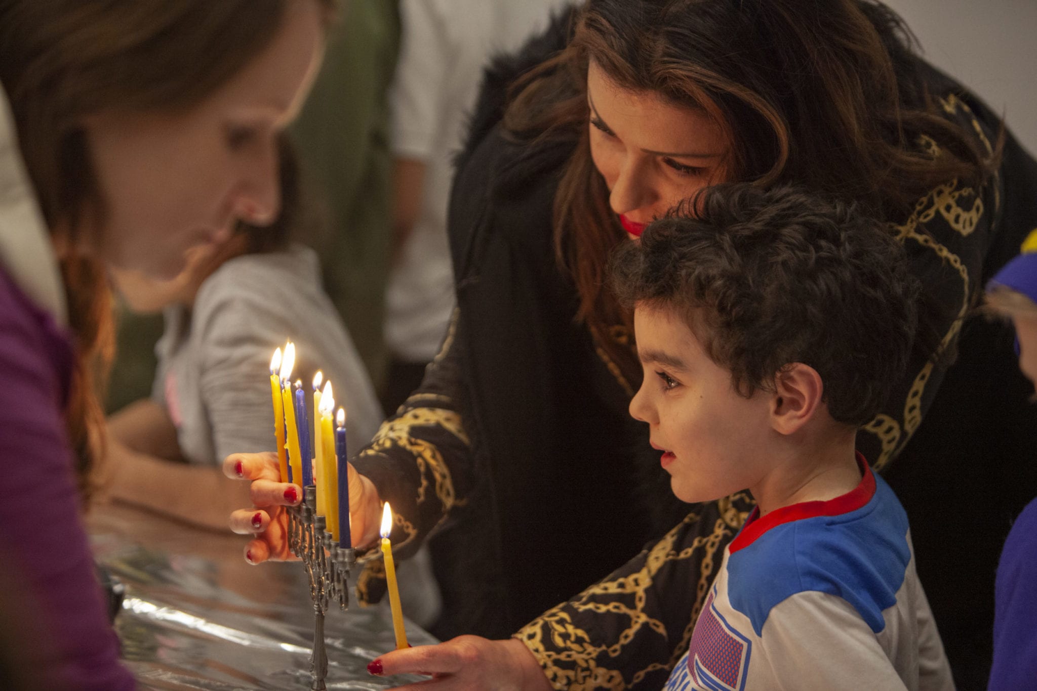 Olgah Goysman and her son Ari light the candles of their family menorah during the children’s Hanukkah festival at Chabad Jewish Center on Dec 9. Photo by Jacob Granneman