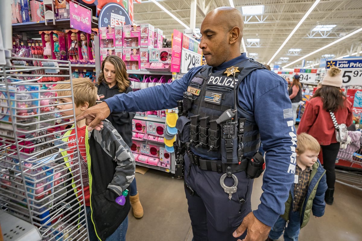 Cowlitz Tribal Police Officer Brandon Molett helps children pick out toys at the eighth annual Shop with a Cop in Woodland. Photo by Mike Schultz