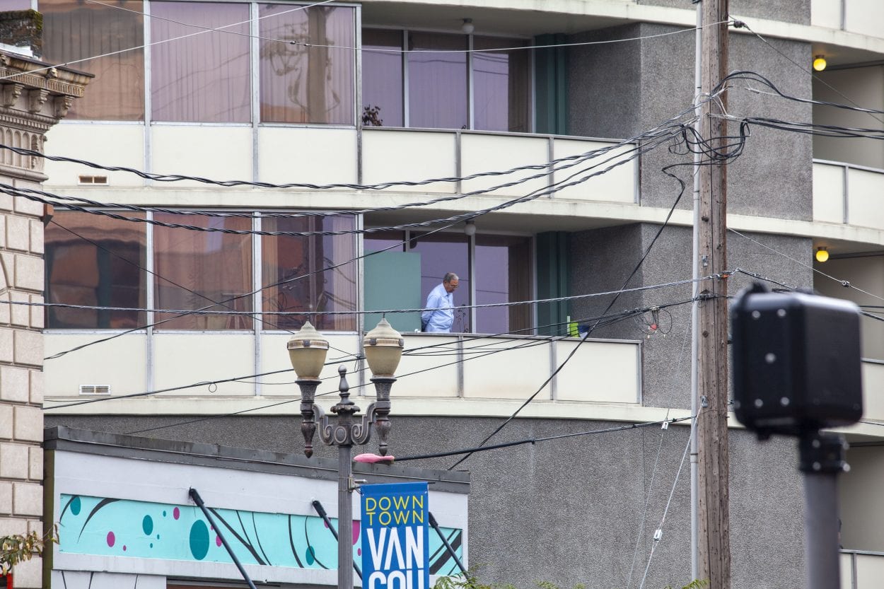 An unidentified man appears on a balcony at Smith Tower in downtown Vancouver where a shooting took place with multiple victims Thursday afternoon. Photo by Johnny Driver