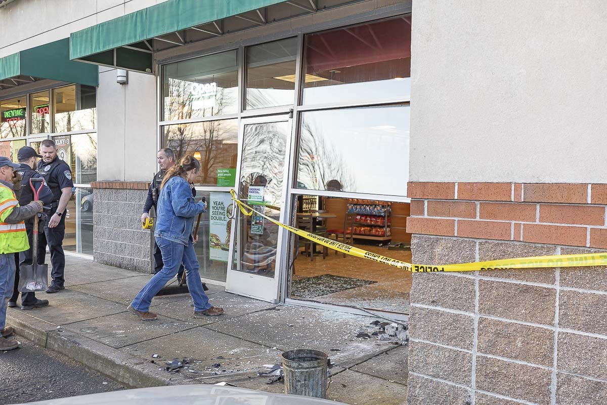 An employee begins cleaning up the mess after a car slammed into the front of a Subway restaurant in Woodland on Sunday. Photo by Mike Schultz