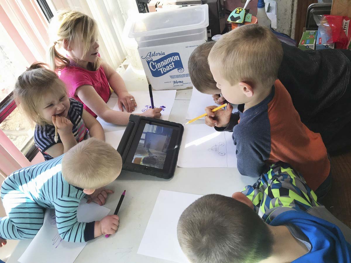Six siblings huddle around a tablet while learning remotely. Photo courtesy of Battle Ground Public Schools