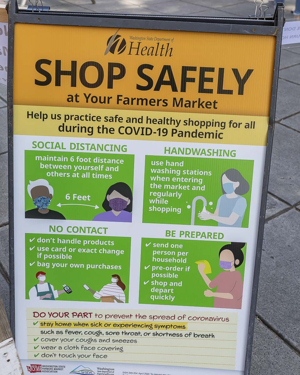Signage like what is shown here, has been placed around and throughout the market to remind shoppers to social distance and if possible, wear masks. Photo by Mike Schultz