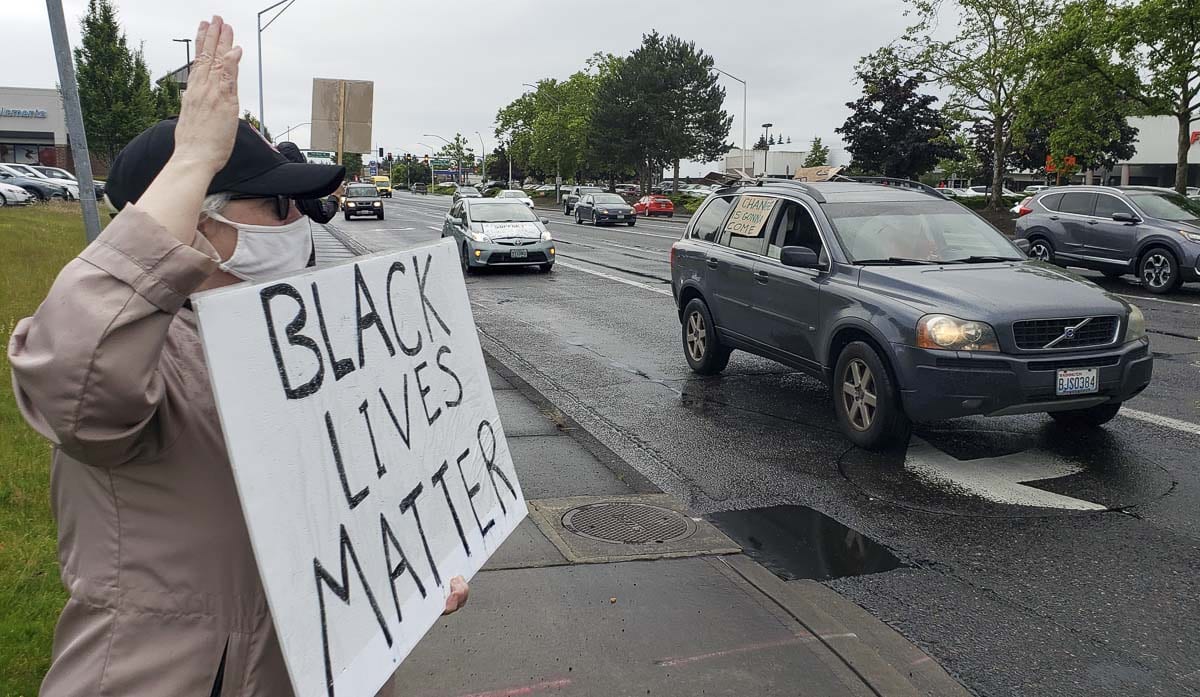 Geni Donaghey, who works at Crestline, holds up a Black Lives Matter sign as a car with more signage passes by Friday night in Vancouver. Black Lives Matter and the Washington Education Association teamed up for a rally. Photo by Paul Valencia