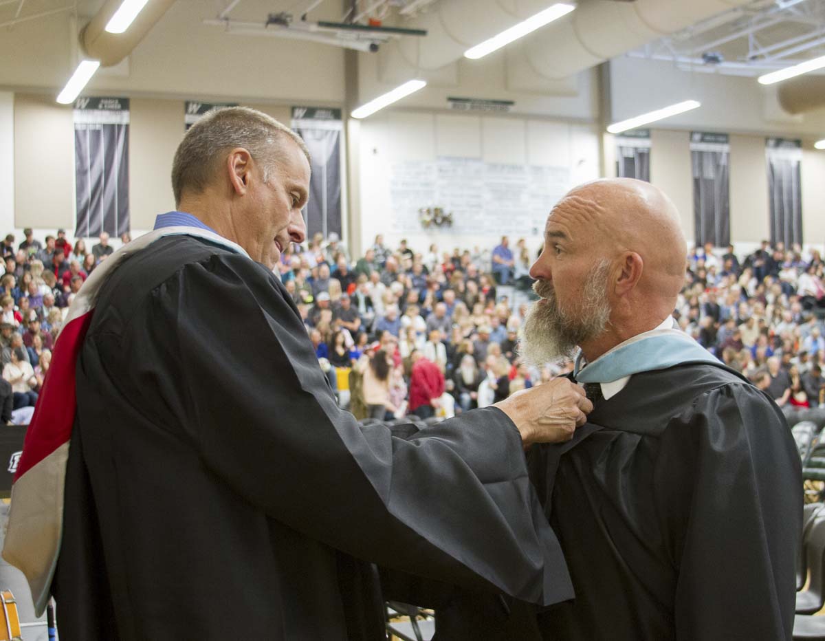 Dan Uhlenkott (left) seen here adjusting John Shoup's (right) hood shortly before the Class of 2019 commencement ceremony, credits John with lessons and coaching that made him a better administrator. Photo courtesy of Woodland Public Schools