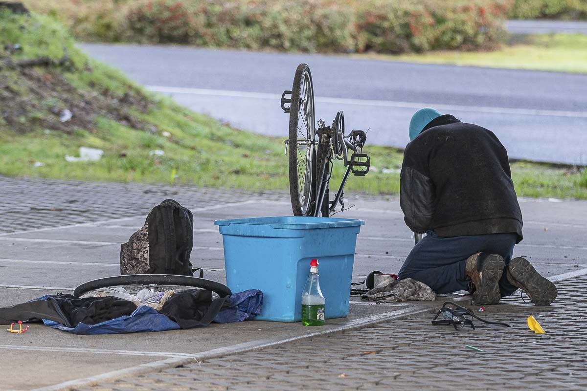 A homeless man works to fix a bicycle underneath the SR-14 overpass at Columbia Way in Vancouver during the Point in Time count on Jan. 30, 2020. Photo by Mike Schultz