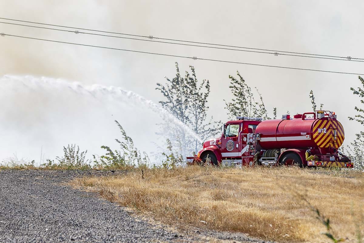 A Vancouver Fire water tender fights a grass fire along Fruit Valley Road on Tuesday. Photo by Mike Schultz