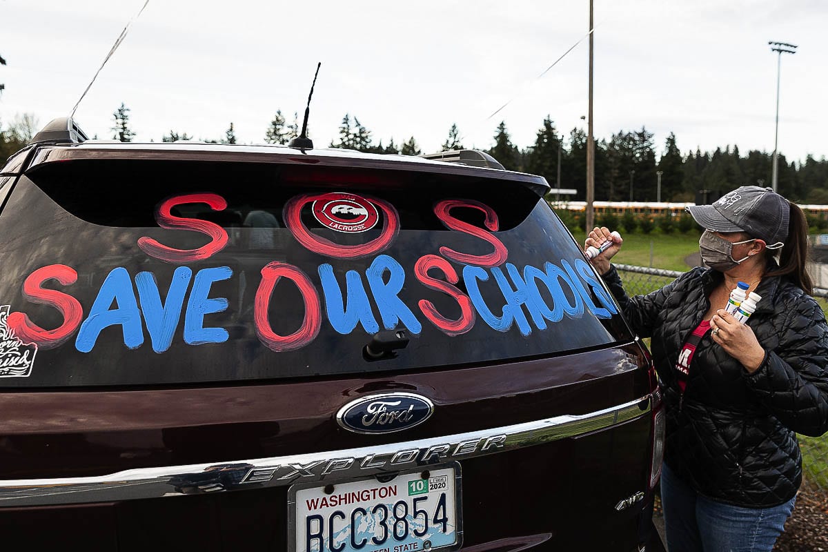 Concerned parent Heather Wynn adds a colorful “Save Our Schools” message to the rear window on her vehicle. Wynn and roughly 30 other vehicles filled with Camas residents joined the rally hoping to bring attention to parents' desire to reopen Camas schools safely for in-classroom instruction. Photo by Mike Schultz