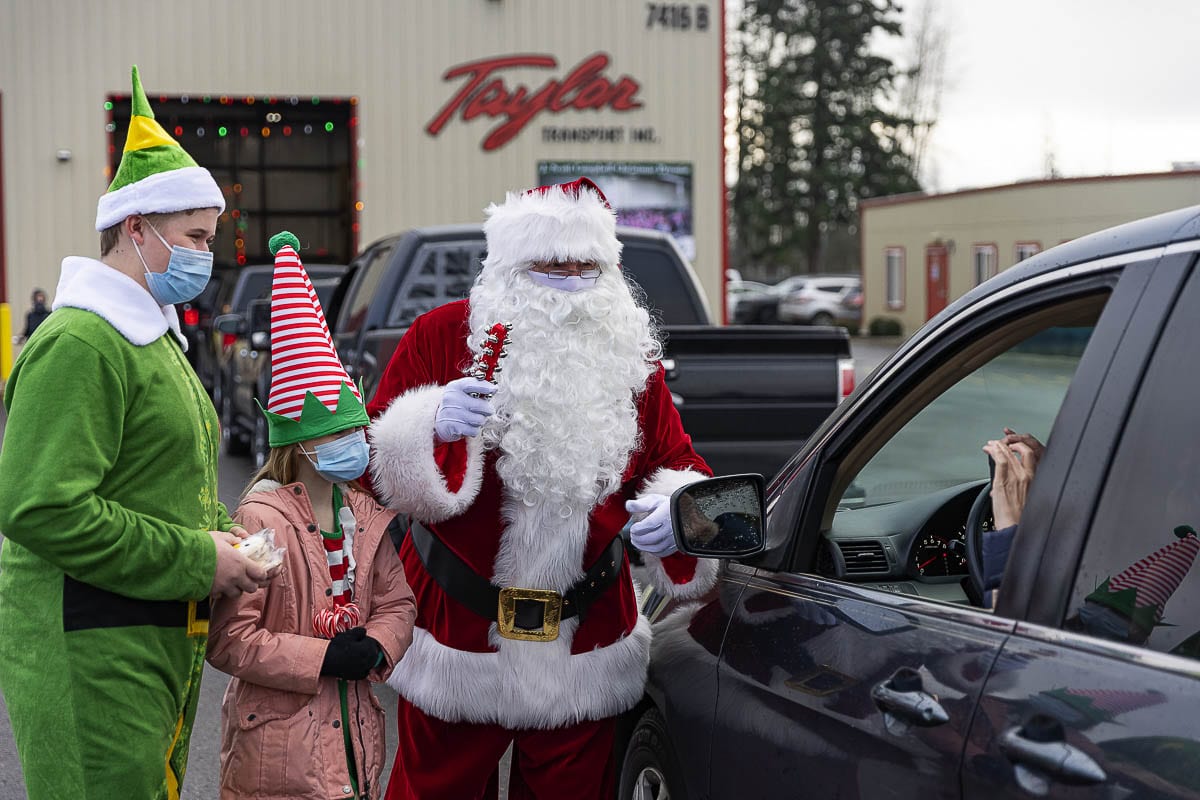 Elves Dylan Johnson and Delaney Baylous help Santa hand out treats to those waiting to pick up bicycles at the Scott Campbell Christmas Promise. Photo by Mike Schultz