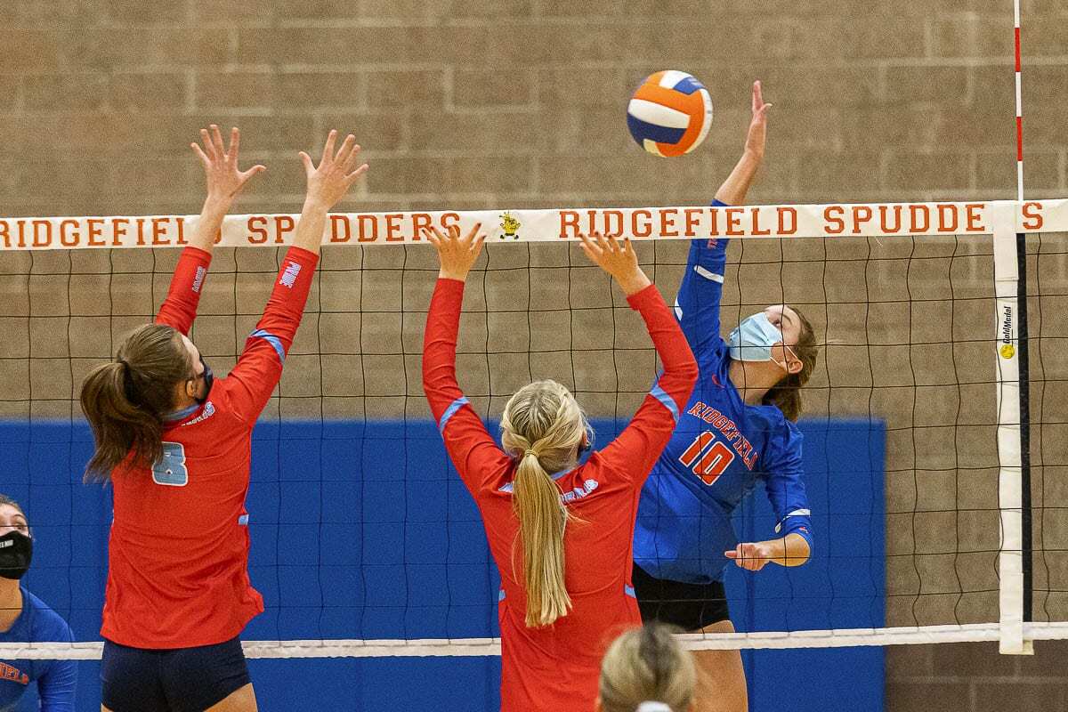 Morgan Harter of Ridgefield rises up to spike it against two Mark Morris defenders Tuesday during their volleyball match. Photo by Mike Schultz