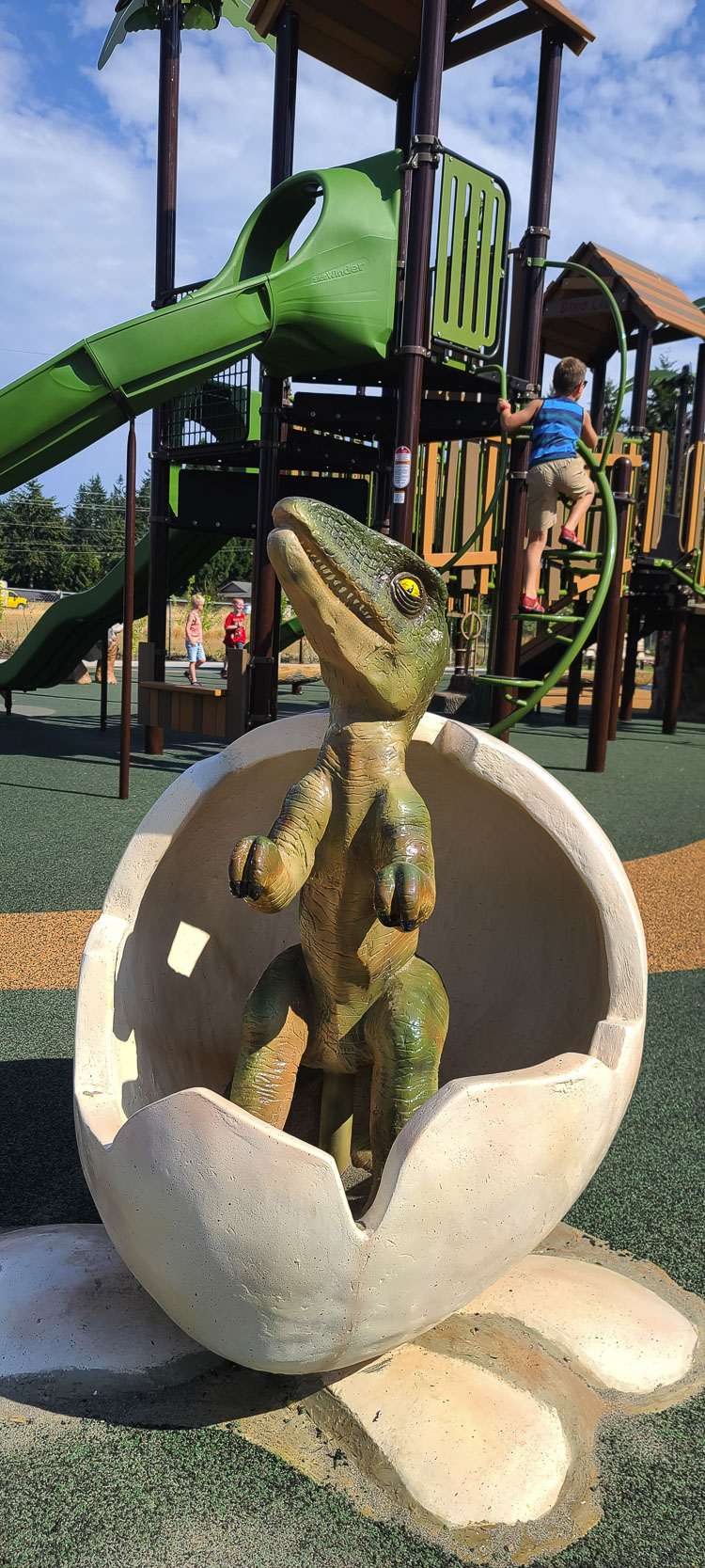 A dinosaur comes to life at a new Vancouver park on 52nd Street and 137th Avenue, as a child climbs into the “Dino Lab” in the background. Photo by Paul Valencia