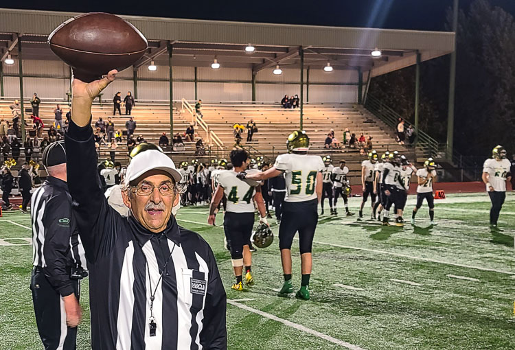 Rick Gilbert holds up the football, signaling the end of Thursday night’s game at McKenzie Stadium. It was also the end of Gilbert’s varsity football officiating career. He is stepping away from varsity action after 36 seasons. Photo by Paul Valencia