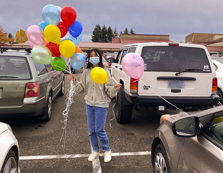 Prairie High School freshman Leena Dang attaches balloons with inspirational messages to cars in the parking lot. Photo courtesy Battle Ground School District