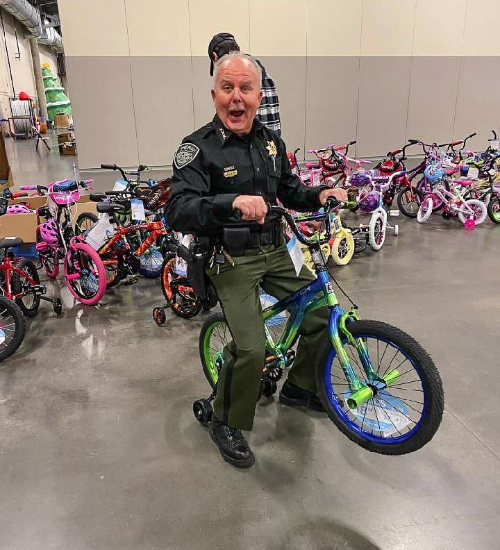 Clark County Sheriff Chuck Atkins tries out a bicycle that Santa’s Posse targeted for an area child. Photo courtesy Clark County Fire District 6