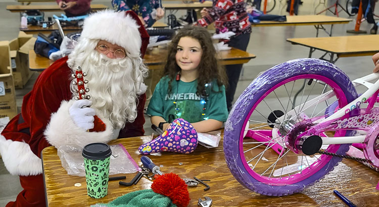 Santa Claus visited with a number of volunteers who were building bikes Saturday, including 7-year-old Storm. Photo by Paul Valencia