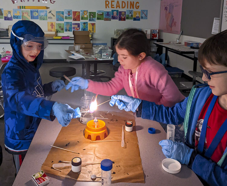 Wisdom Ridge K-3 students (left to right) Archer Woods, Callie Klein, and Jakob Wagoner learn chemistry by changing flame colors. Photo courtesy Ridgefield School District