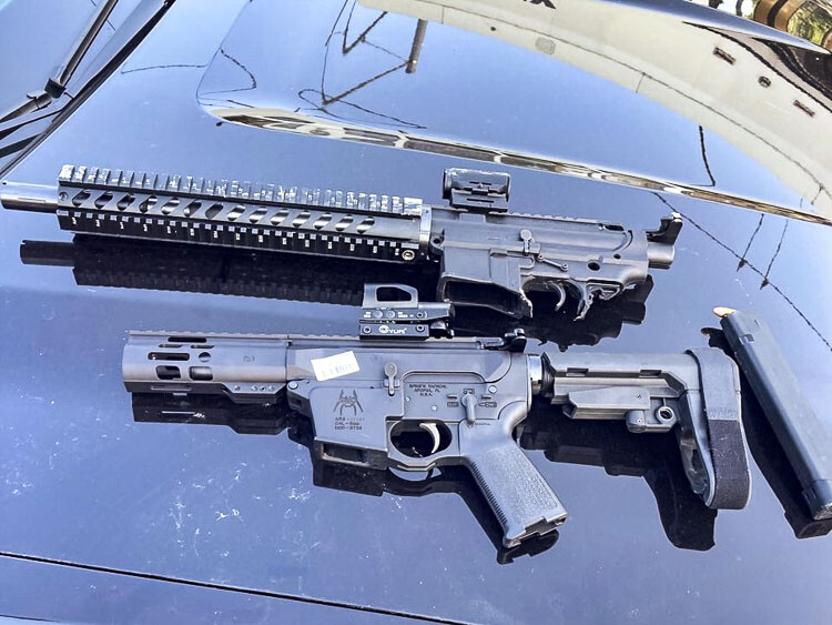 Two black rifles, heavily damaged, displayed on a vehicle hood, loaded magazine nearby. Photo courtesy Portland Police Bureau