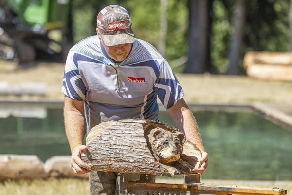 Bob King shows off the bear he created with a chainsaw. Photo by Mike Schultz