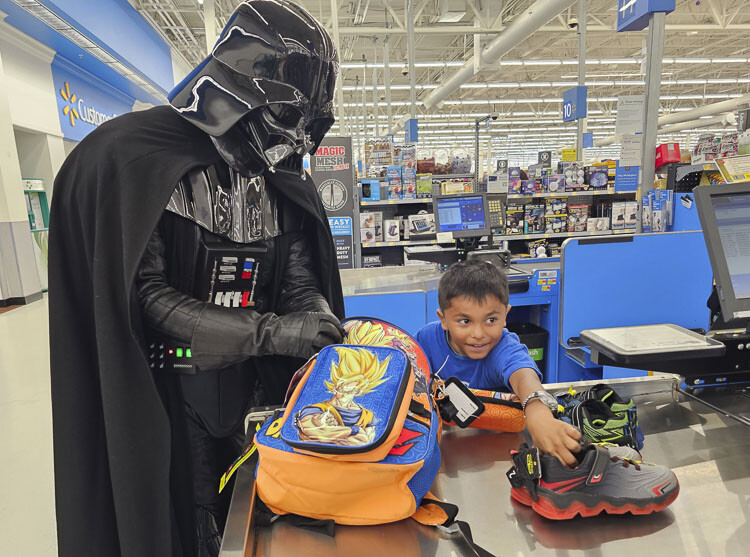 Darth Vader helps Jordan, 7, load up his backpack Tuesday after a shopping spree at Walmart. It was part of Uplift!, a program organized by the Southwest Washington Center for the Arts, to expose children to the arts and allow them to have a shopping spree. Photo by Paul Valencia