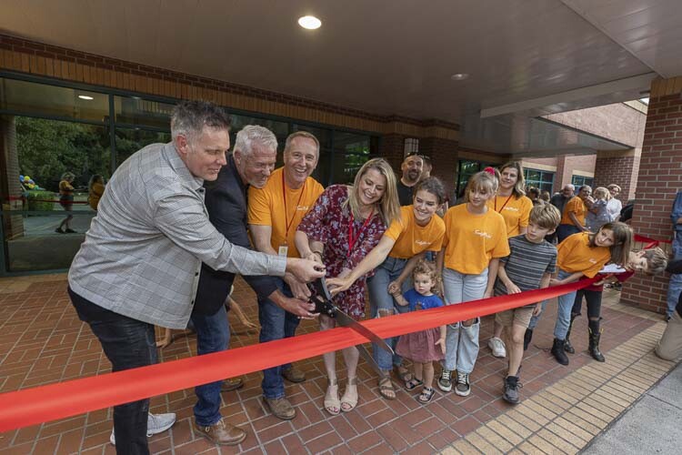 Jay and Heidi St. John (third and fourth from left) and family members perform the ceremonial cutting of the ribbon at the grand opening of the Firmly Planted Homeschool Resource Center Wednesday. Photo by Mike Schultz