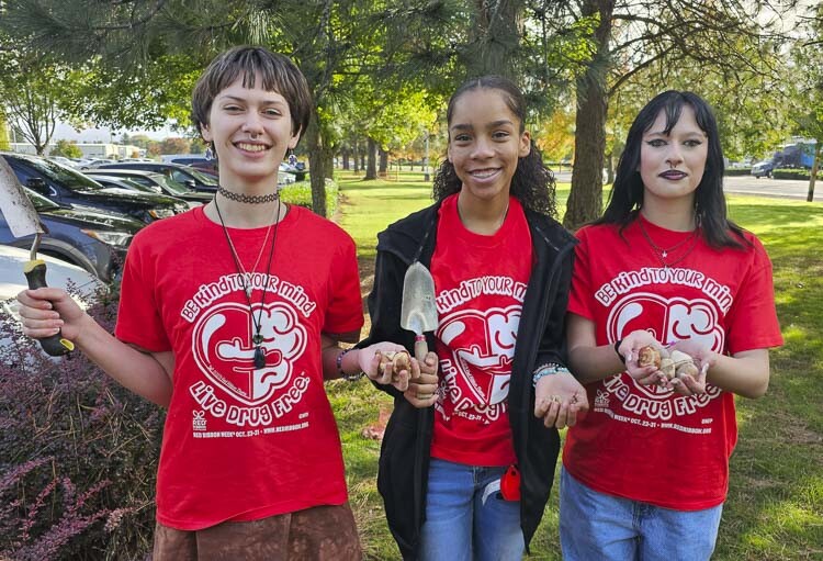 Fort Vancouver sophomores, left to right, Bella Geddes, Emaunie Bush, and Ruby Geddes took a break from planting tulips Monday to show off their shirts. Be Kind to Your Mind is the motto of the school’s Prevention Club. Photo by Paul Valencia