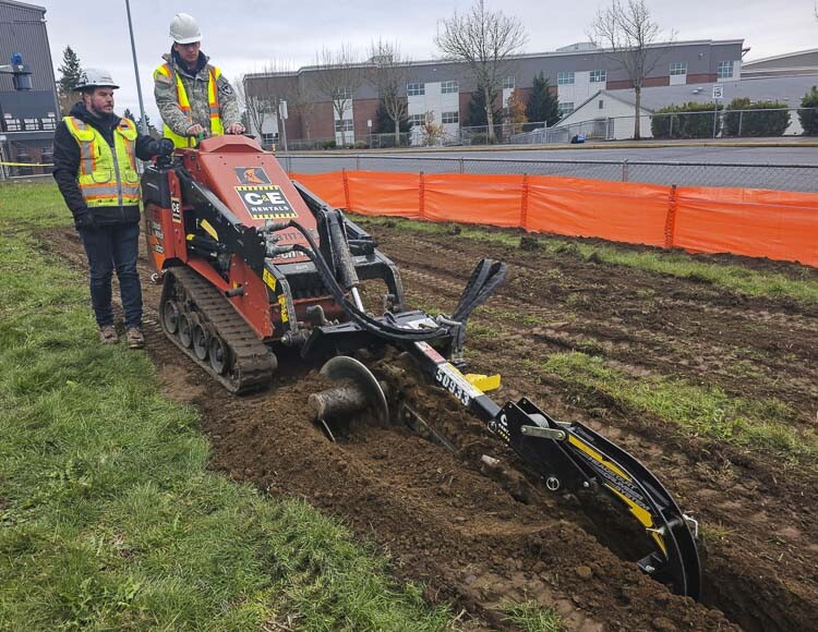 Evergreen student Steven Jacka said he wished he had a trencher like this when he helped on a family project last summer. Jacka was operating the machine Thursday, under the direction of Anrew Palomaki of Tapini, Inc., as part of Dig Day at Evergreen High School. Photo by Paul Valencia