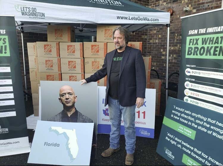 Let's Go Founder Brian Heywood poses in front of boxes of initiative signatures, along with a photo of billionaire Amazon founder Jeff Bezos and the state of Florida. Bezos announced earlier this year he intends to move from Washington to Florida. Photo courtesy Brett Davis