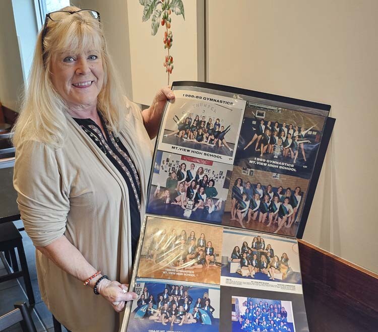Cristi Westcott holds up a page featuring just some of the many teams she has coached. Westcott is retiring after more than 40 years of high school gymnastics coaching, the last 40 with the Mountain View Thunder. Photo by Paul Valencia