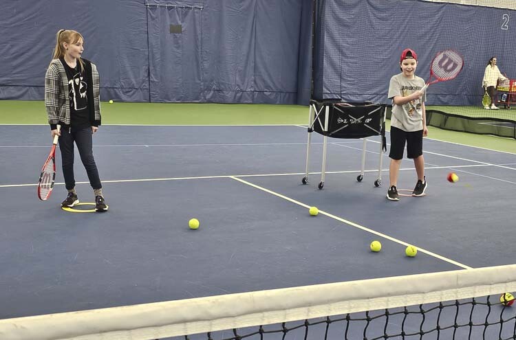Alexandria Bauer waits her turn as Evan Tooley takes a swing at a Just Serve Autism tennis class last week at the Vancouver Tennis Center. Photo by Paul Valencia