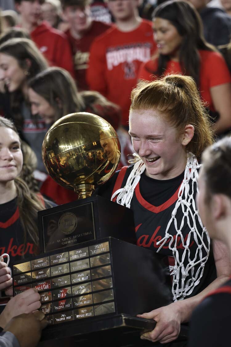 Camas standout Addison Harris (33) shows off the state championship trophy while wearing one of the nets she and her teammates cut down after Saturday’s championship game. Photo courtesy Mike Schultz