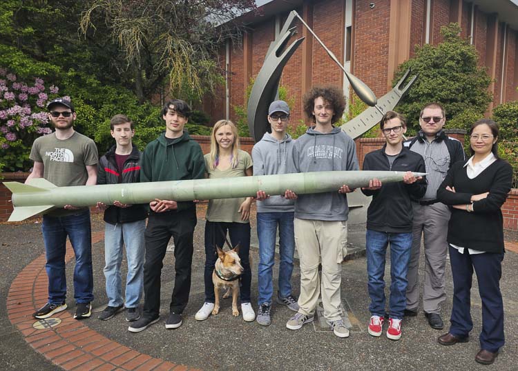 Members of the Clark Aerospace and Robotics program from Clark College hold “Emperor Penguin,” their rocket that will be used at Spaceport America Cup, the largest intercollegiate rocket engineering competition. Pictured: Bladen Mitchell, Eric Holtz, Alex Kari, Rebekah Irvin (and service-dog-in-training Zmeya), Arthur Strulev, Ethan Walters, Max Baugess, Vyacheslav Lukiyanchuk, and advisor Sophie Lin.