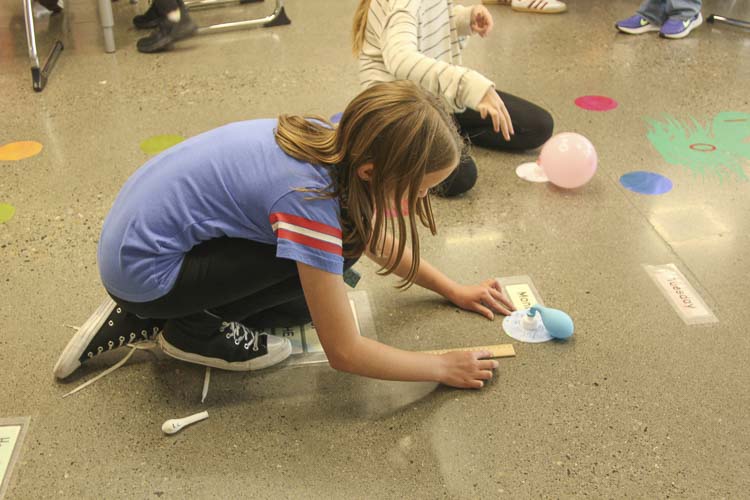 A student measures the distance traveled by balloon-powered hovercraft. Photo courtesy Washougal School District