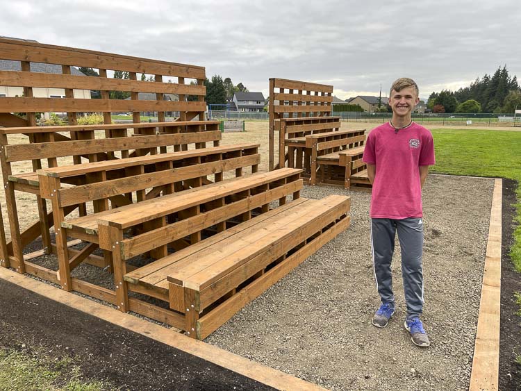 Noah Aarhus stands in front of new bleachers at Hillcrest Church, to be used for parents and fans to watch their children play UPWARD sports. Aarhus, 17, coordinated the project to have the bleachers built and installed as part of his Eagle Scout project. Photo courtesy Aarhus family