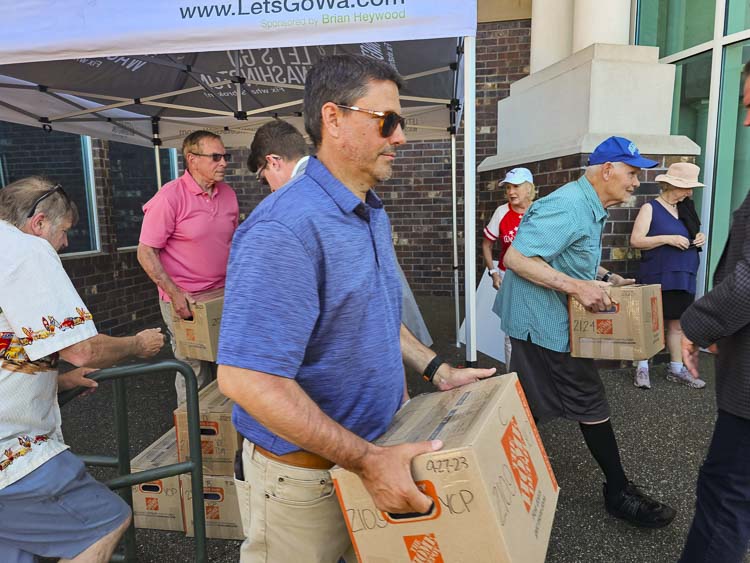 Volunteers move boxes of I-2066 petitions from office steps to a cart for the Secretary of State office staff to begin validating signatures. This was the second largest number of signatures in the history of Washington. Photo by John Ley