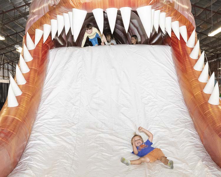 Cullen Matson of Brush Prairie shows off his teeth with a big smile after escaping the giant teeth of this dinosaur at the dinosaur obstacle course at the Clark County Fair. Photo by Mike Schultz