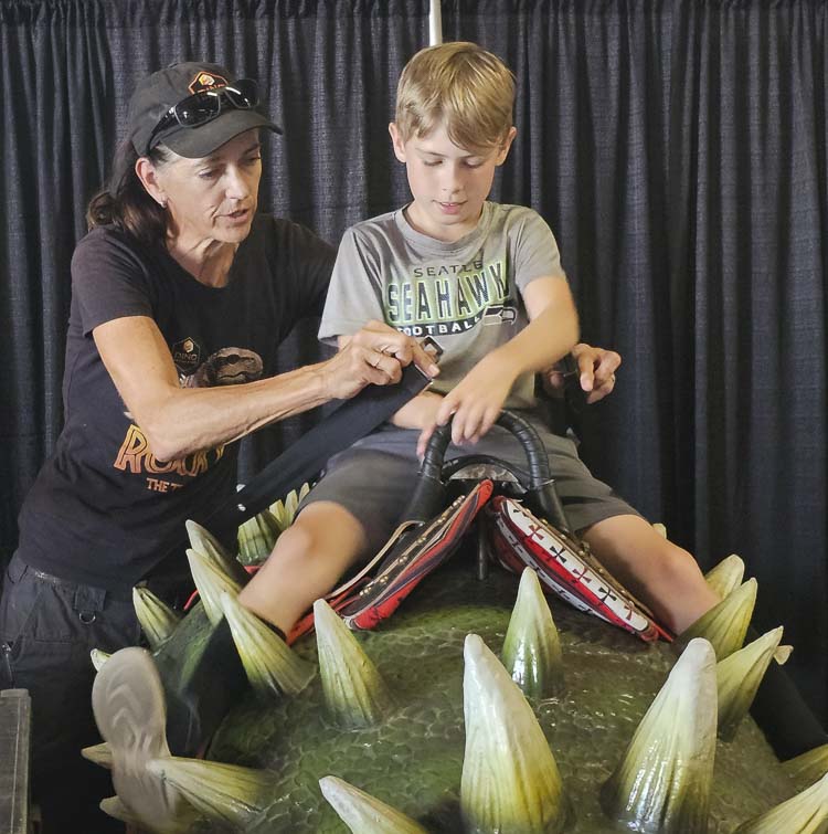 Keri DeWitt, owner of Dino Encounters, helps Lewis Antonini Kearns of Vancouver get ready to take a ride on a dinosaur Friday at the Clark County Fair. Photo by Paul Valencia