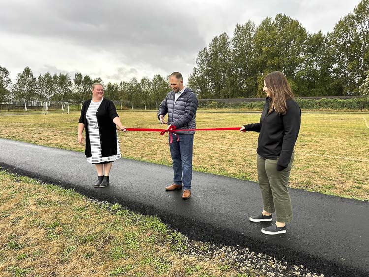 The principal of Columbia Elementary School in Woodland, David Starkey, cuts the ribbon with the help from Katie Murdock, left, and Kellie Tooley, representing the Woodland Parent Teacher Student Association. An asphalt track was built at Columbia Elementary thanks to community donations and more. Photo courtesy Woodland PTSA