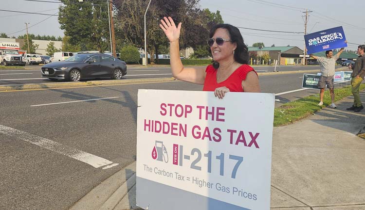 Stephanie McClintock, a Washington state representative, waves as drivers pass by a gas station Friday at a Let’s Go Washington event. Photo by Paul Valencia