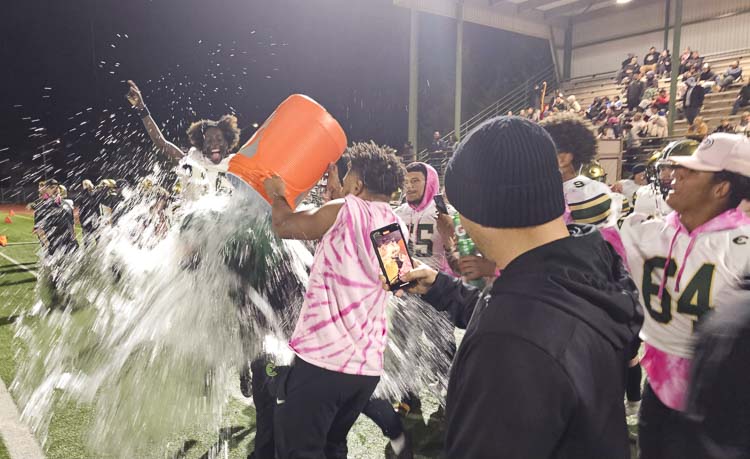 Evergreen coach Christian Swain gets soaked by his team in the closing seconds of Evergreen’s win over Heritage on Friday night, a victory that clinched a league title for the Plainsmen. Photo by Paul Valencia