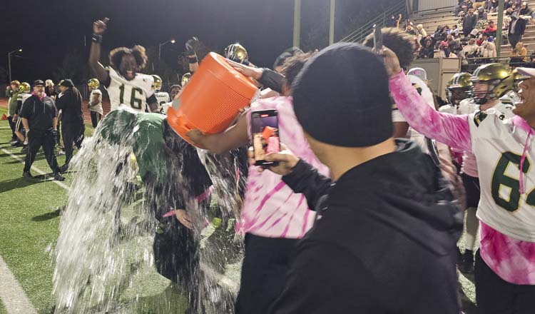 Christian Swain was smart enough to put his hoodie over his head just before his Evergreen football players celebrated their league title by soaking their head coach. Photo by Paul Valencia