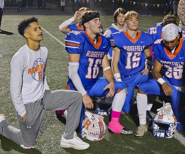 Brian McLemore III, left, listens in during Ridgefield’s post-game meeting after the Spudders beat Washougal 21-0 on Friday. McLemore is recovering from a major surgery and will not play for the rest of this season, but he has vowed to return to the field next year. Photo by Paul Valencia