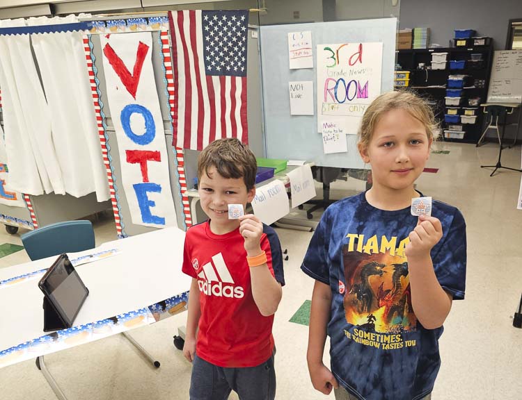 Grady Englebart, left, and Louie Petrasek, students at Salmon Creek Elementary School in Vancouver, hold up their “I voted” stickers last week during the election for the new mascot to represent all third-graders at the school.