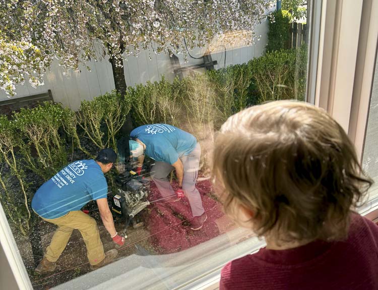 Marcella, a 3-year-old, watches workers from Rick’s Custom Fencing and Decking as they put in a new fence. Photo courtesy Taylor Stanley